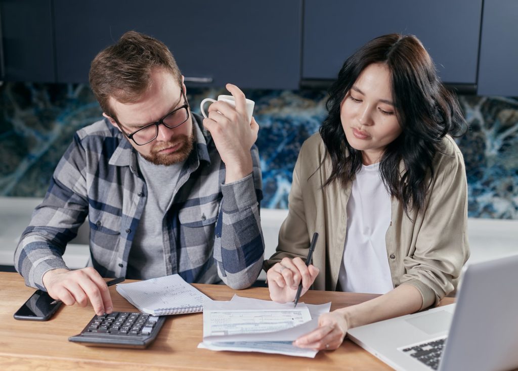 A man and woman discussing their bills and dealing with the effects of financial stress.