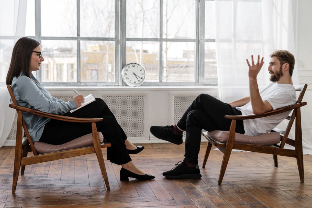 A client talking to a therapist or psychiatrist in an office.