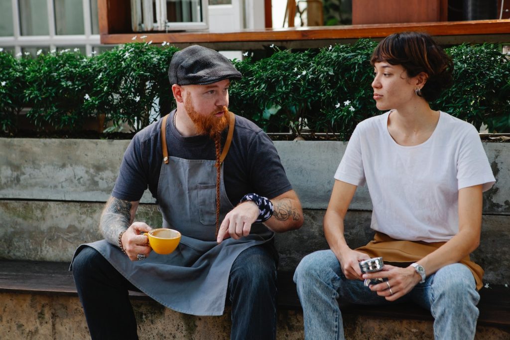 Two people making small talk on a bench.