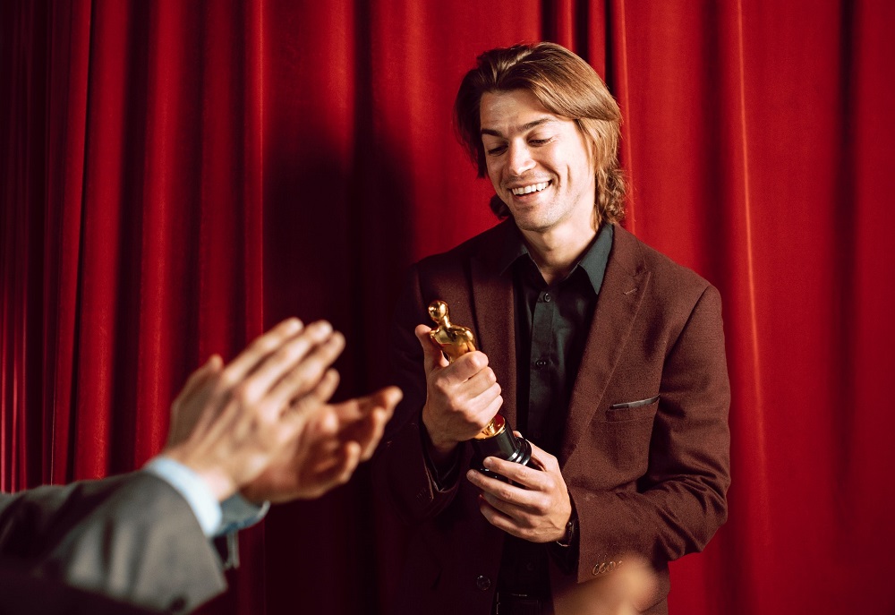 Man holding trophy and smiling, symbolizing a narcissist.