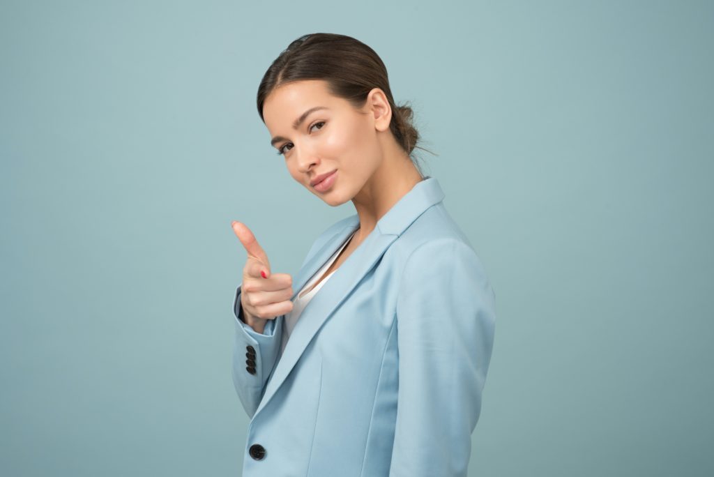 A woman pointing confidently at the viewer, demonstrating body language that's assertive without being rude.