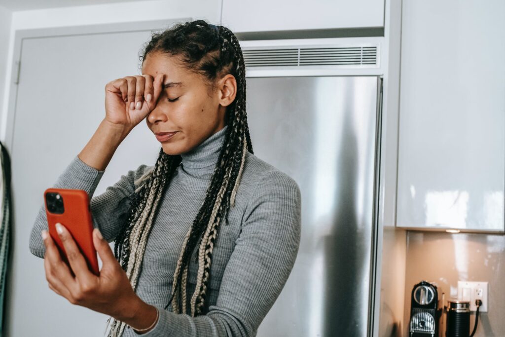 Young woman looking at her phone, feeling stress from current events.